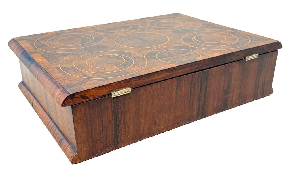 A shallow rectangular William and Mary period wooden box with laburnum oyster veneered patterns, concentric circular stringing on the lid, and a brass keyhole escutcheon on the front panel. View IX