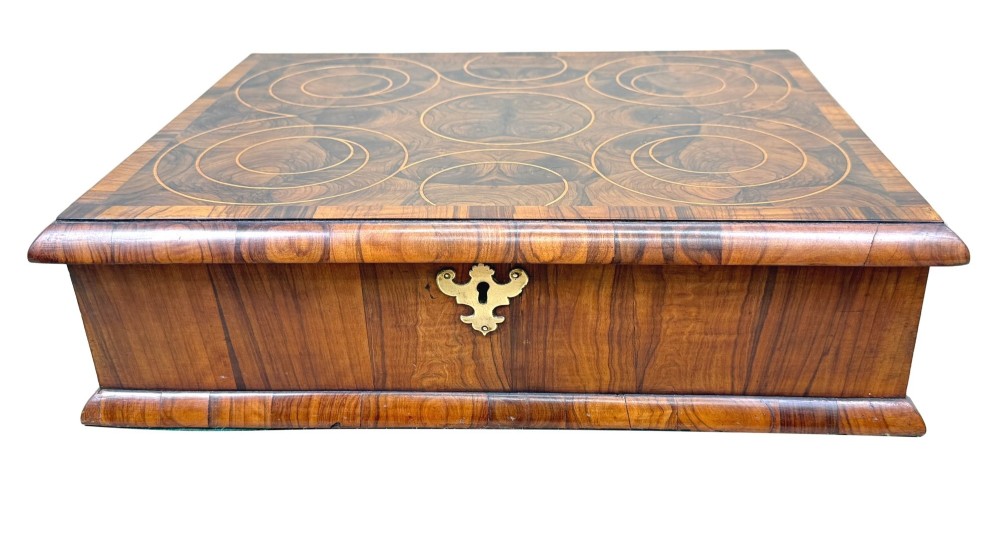 A shallow rectangular William and Mary period wooden box with laburnum oyster veneered patterns, concentric circular stringing on the lid, and a brass keyhole escutcheon on the front panel. View XII