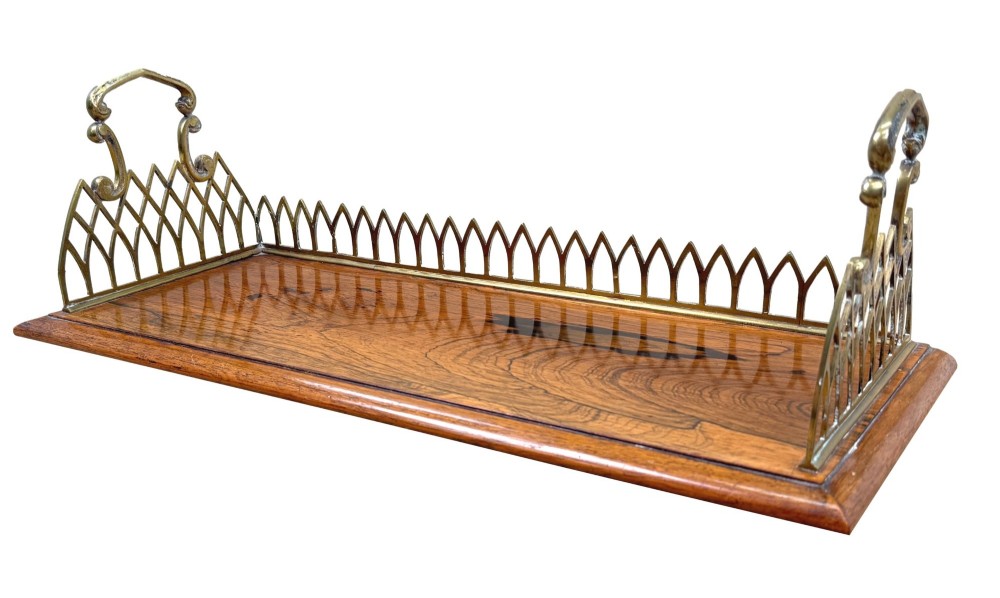 A rectangular rosewood desk tray with a polished grain surface, featuring decorative pointed brass gallery borders and arched carrying handles at each end.