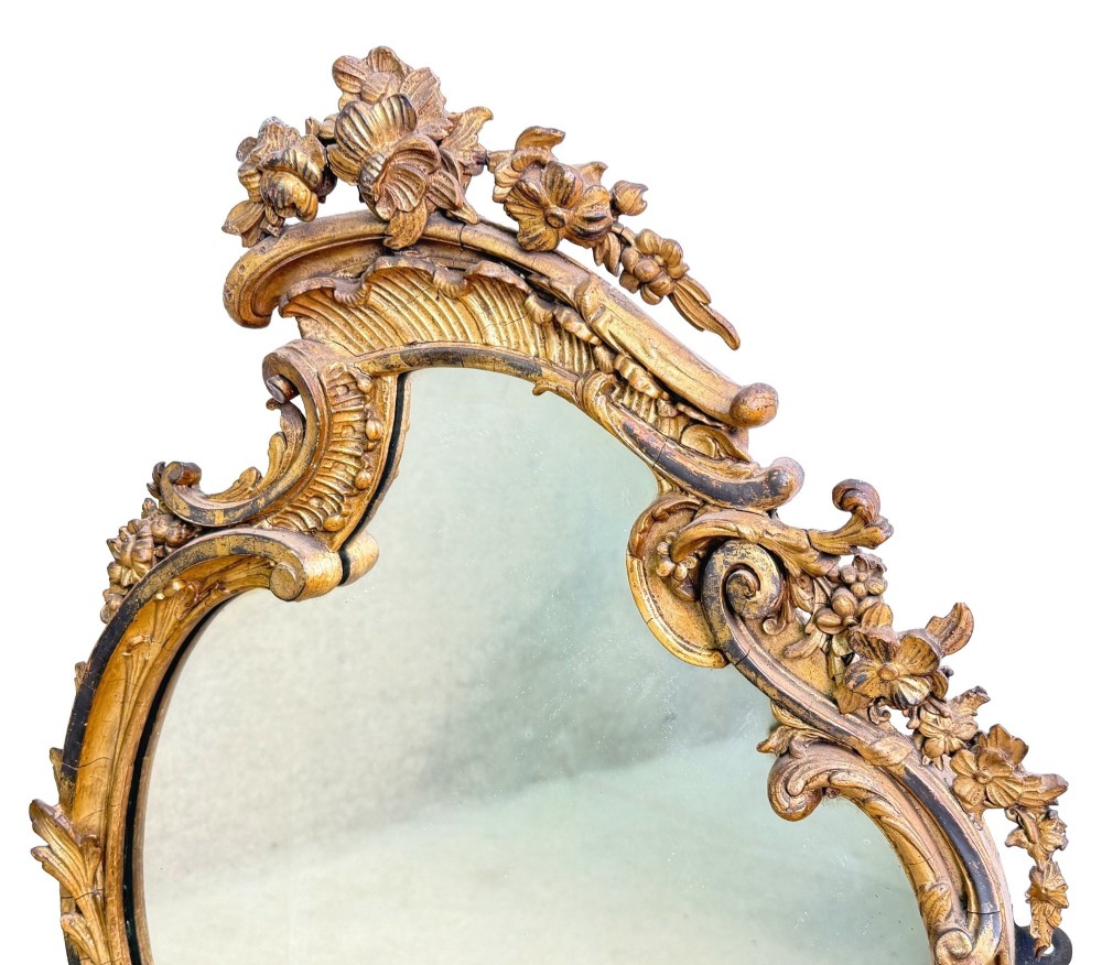 A pair of mid-19th-century cartouche-form wall mirrors featuring ornate carved giltwood and gesso frames decorated with scrolling foliage and floral cresting. View IV