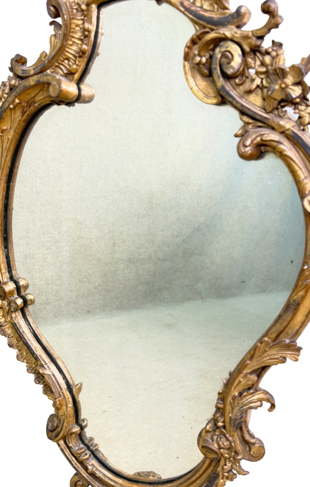 A pair of mid-19th-century cartouche-form wall mirrors featuring ornate carved giltwood and gesso frames decorated with scrolling foliage and floral cresting. View VII