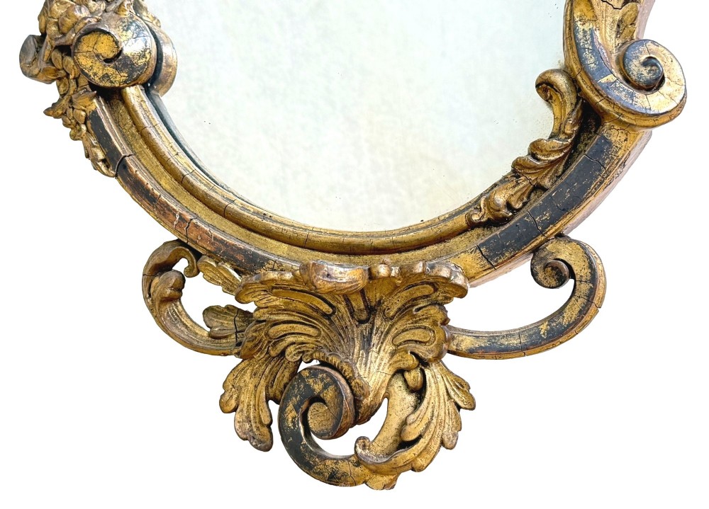 A pair of mid-19th-century cartouche-form wall mirrors featuring ornate carved giltwood and gesso frames decorated with scrolling foliage and floral cresting. View VIII