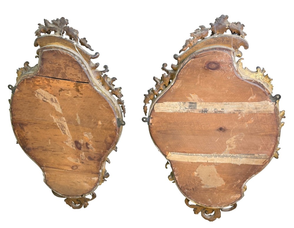 A pair of mid-19th-century cartouche-form wall mirrors featuring ornate carved giltwood and gesso frames decorated with scrolling foliage and floral cresting. View XIII