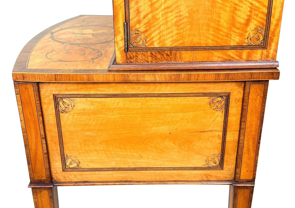 A 19th-century inlaid satinwood display cabinet featuring an arched cresting, glazed upper doors, marquetry frieze drawers, and square tapered legs. View V