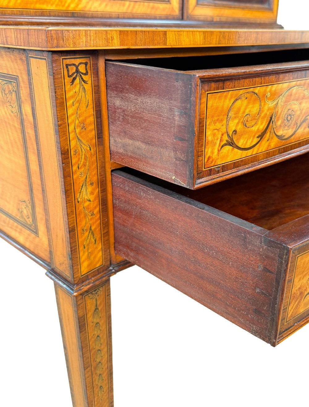 A 19th-century inlaid satinwood display cabinet featuring an arched cresting, glazed upper doors, marquetry frieze drawers, and square tapered legs. View XI