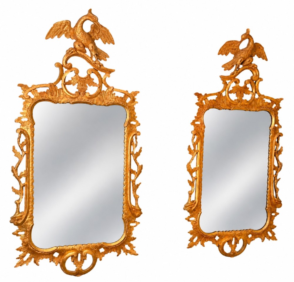 A pair of 18th-century Chippendale style giltwood wall mirrors featuring carved Rococo scroll frames topped with bird crests.