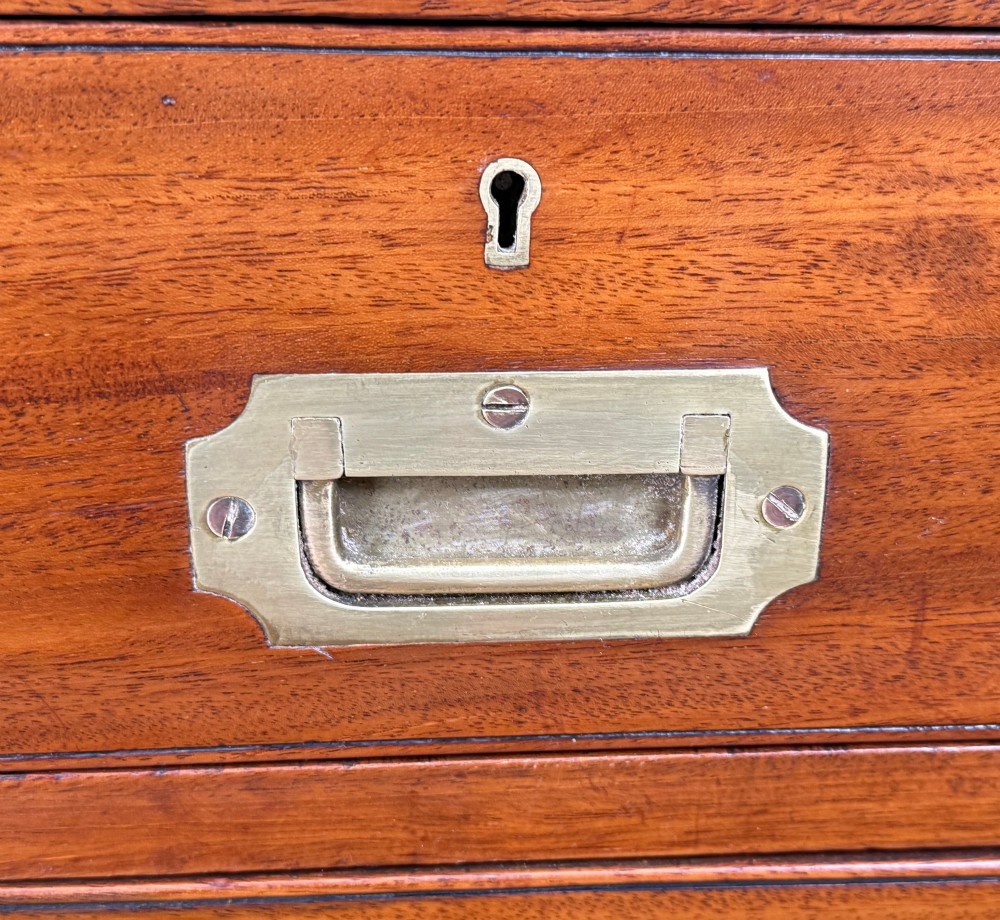 A mid-19th century camphor wood military campaign chest of drawers featuring brass corner brackets, flush handles, and two separate stacking sections on turned feet. View VIII