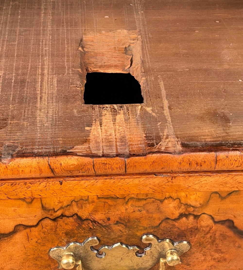 An early eighteenth-century Queen Anne walnut chest of drawers featuring two short over three long graduated drawers, brass handles, pierced escutcheons, and turned bun feet. View X