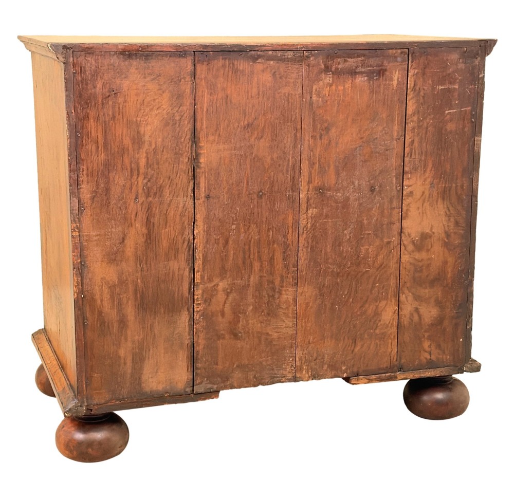 An early eighteenth-century Queen Anne walnut chest of drawers featuring two short over three long graduated drawers, brass handles, pierced escutcheons, and turned bun feet. View XIV