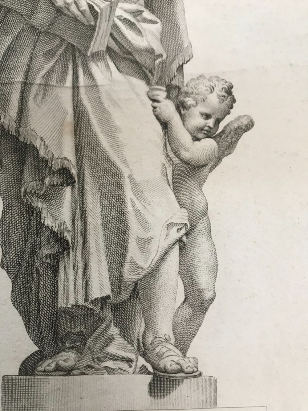 An 18th-century monochrome copperplate engraving depicting a classical draped statue of Saint Matthew holding a book alongside a winged cherub on a plinth. View II