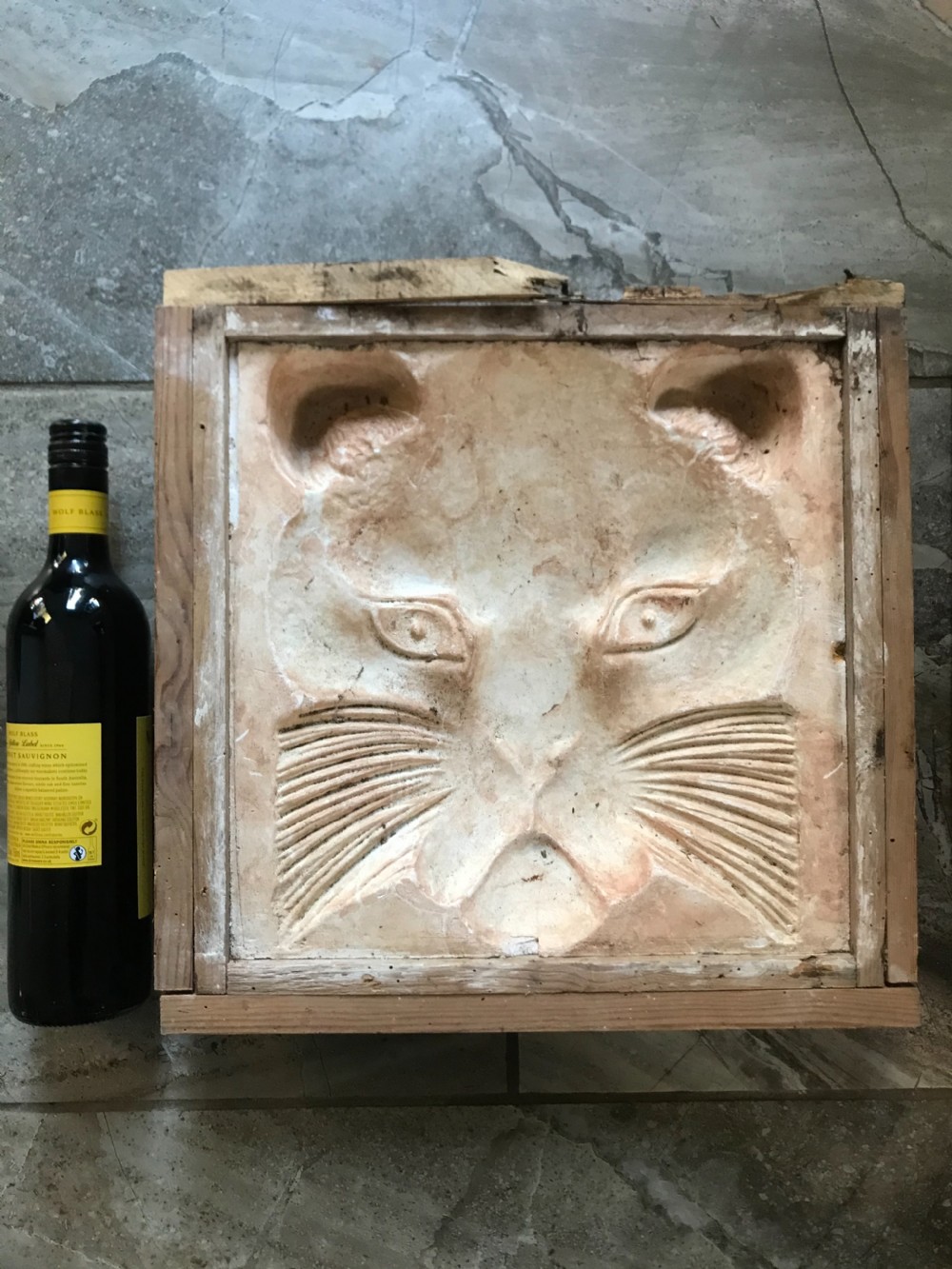 A 19th-century relief plaster mould displaying an incised carving of a cats face set within a square wooden frame. View II