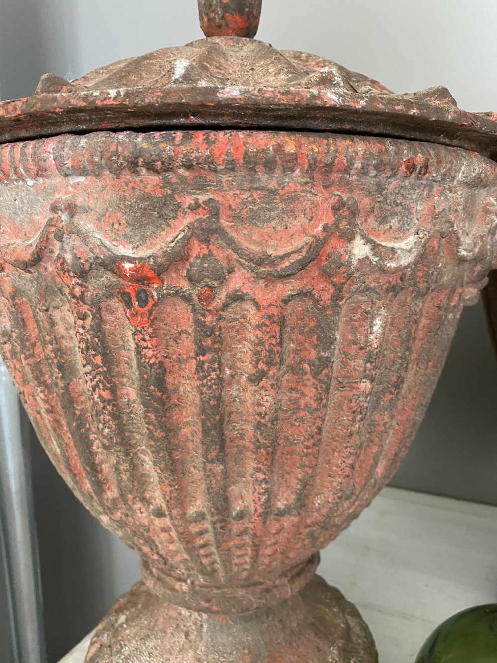A pair of antique cast iron urns with fluted bodies, finial-topped lids, and weathered red patinated surfaces resting on pedestal bases. View III