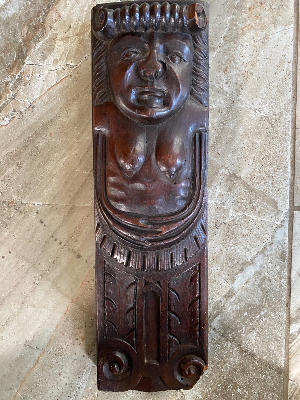 A dark brown 17th-century carved oak caryatid panel depicting a stylised female figure with carved scrollwork details.