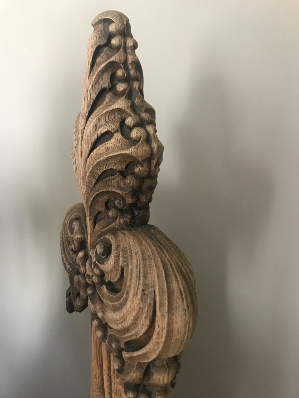 An 18th-century hand-carved oak poppy head feature with Gothic foliate leaf motifs tapering into a shaped timber bench terminal. View II