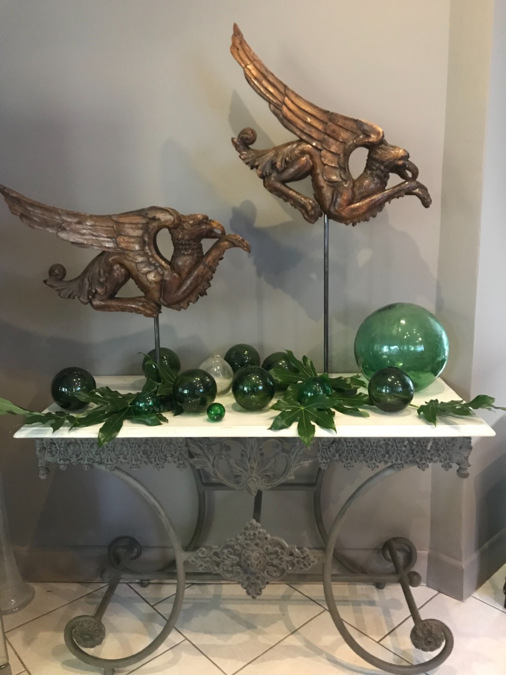A pair of 19th-century carved walnut winged griffin sculptures mounted on slender dark metal display stands. View II