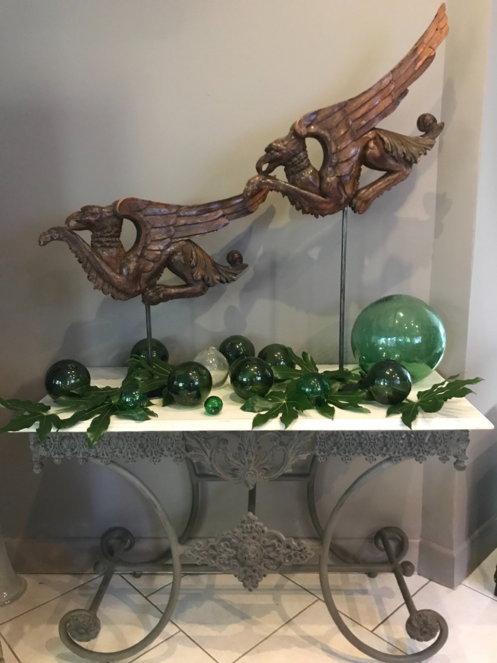A pair of 19th-century carved walnut winged griffin sculptures mounted on slender dark metal display stands. View III