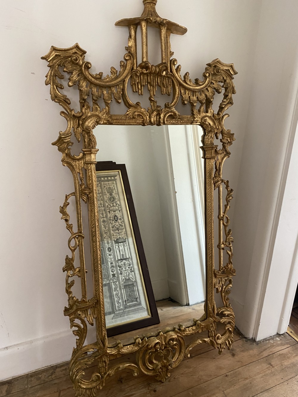 An ornate giltwood Chippendale style wall mirror featuring elaborate carved acanthus scrolls, openwork detailing, and a central pagoda crest.