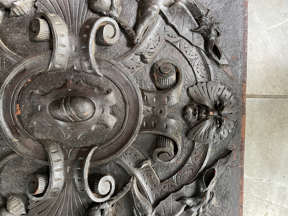 A rectangular dark walnut wood panel featuring high-relief carvings of a Green Man mask, mythical winged beasts, scrolls, and foliate motifs. View II