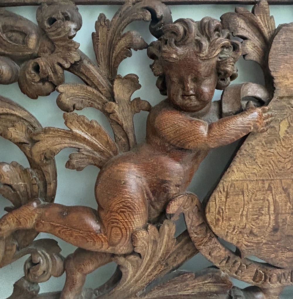 A wide 17th-century dark oak architectural panel intricately carved in high relief with scrolling acanthus leaves and central cherub figures. View III