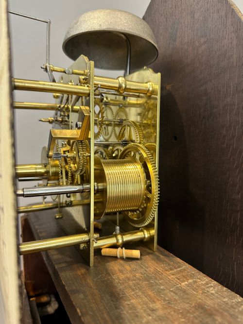 fig 6. A Regency flame mahogany longcase clock featuring a pointed arch hood, white circular dial signed by Thomas Wightman of London, and brass column details.