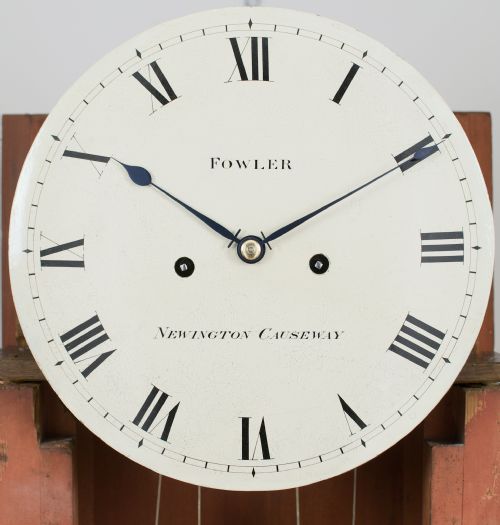 fig 1. A Georgian tall mahogany longcase clock featuring an arched hood, a circular dial with Roman numerals, and brass fluted quarter columns.