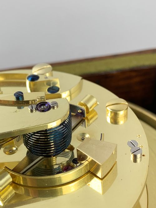 fig 3. An antique 19th-century brass-bound wooden box opening to reveal a gimballed marine chronometer clock with a silvered dial and Roman numerals.