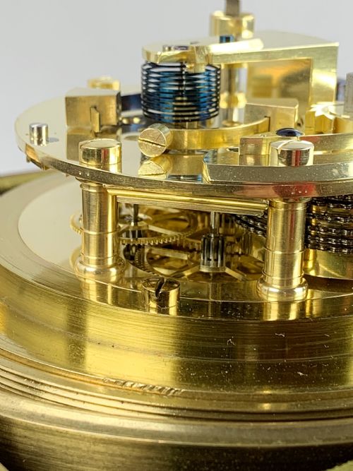 fig 4. An antique 19th-century brass-bound wooden box opening to reveal a gimballed marine chronometer clock with a silvered dial and Roman numerals.
