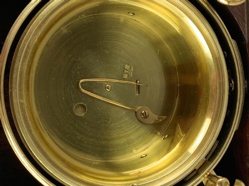 fig 7. An antique 19th-century brass-bound wooden box opening to reveal a gimballed marine chronometer clock with a silvered dial and Roman numerals.