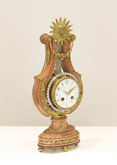 fig 2. A Louis XVI style lyre-shaped mantel clock featuring pink marble, gilt bronze ormolu mounts, and a central white enamel dial.