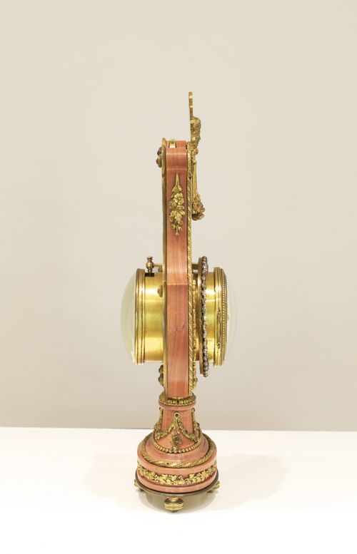 fig 3. A Louis XVI style lyre-shaped mantel clock featuring pink marble, gilt bronze ormolu mounts, and a central white enamel dial.