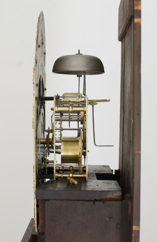 fig 3. An 18th-century Georgian longcase clock featuring a dark wooden cabinet, an arched hood with a finial, and a brass dial with silvered chapter ring.