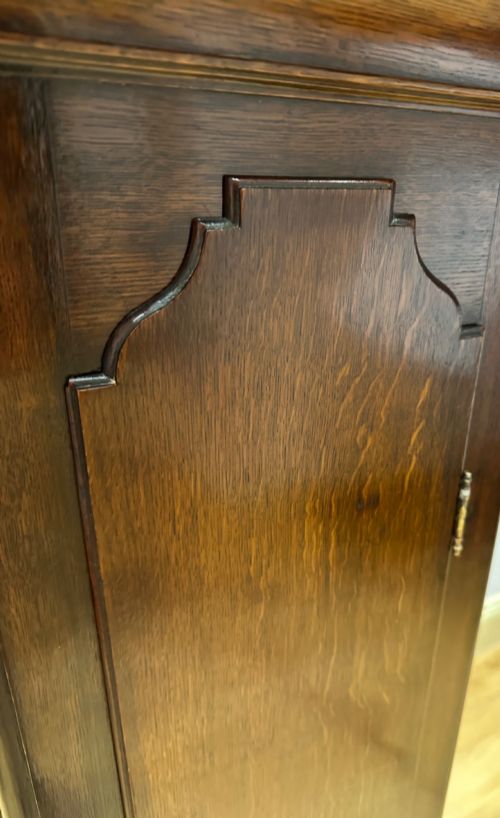 fig 8. An 18th-century Georgian longcase clock featuring a dark wooden cabinet, an arched hood with a finial, and a brass dial with silvered chapter ring.