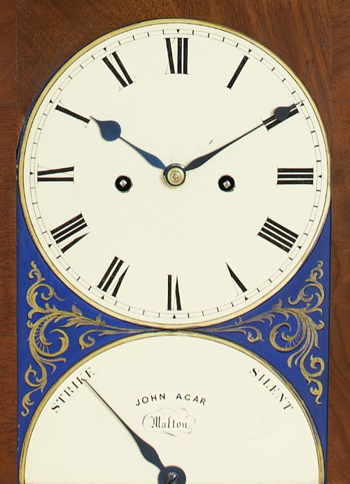 fig 4. A Georgian mahogany bracket clock featuring a brass pineapple finial, brass side handles, a white dial with Roman numerals, and a lower strike-silent mechanism.