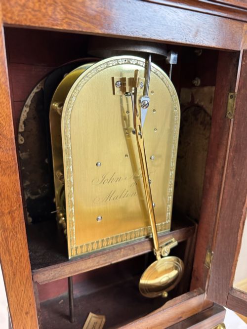 fig 7. A Georgian mahogany bracket clock featuring a brass pineapple finial, brass side handles, a white dial with Roman numerals, and a lower strike-silent mechanism.