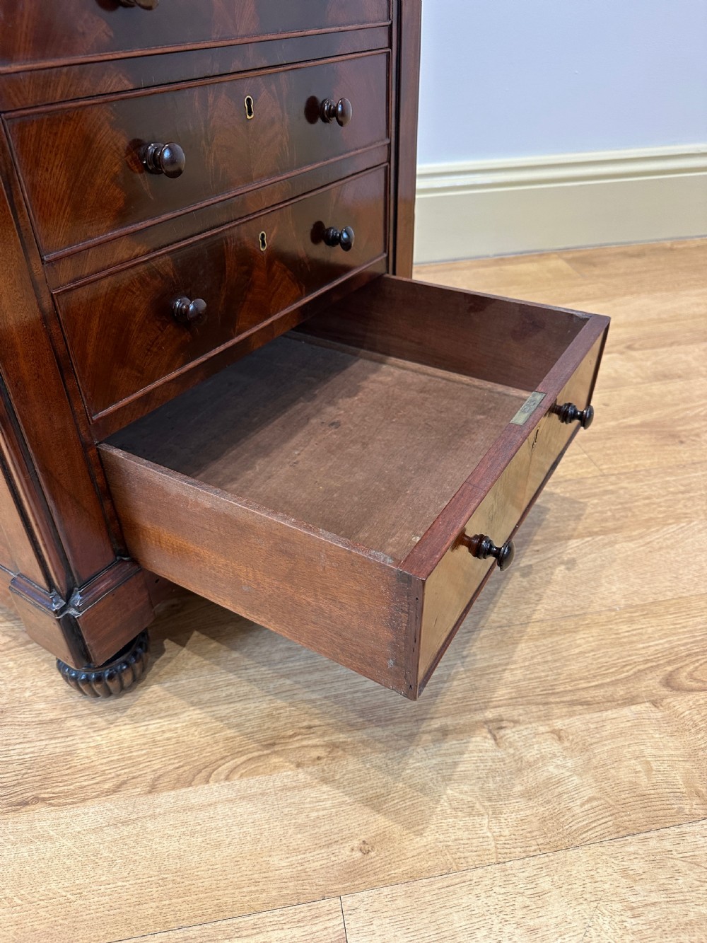 An antique Georgian mahogany Davenport desk featuring a sloped leather writing surface, decorative brass gallery, and side-mounted drawers. View X