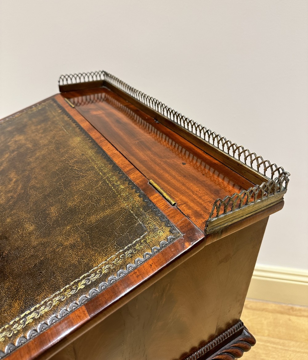 An antique Georgian mahogany Davenport desk featuring a sloped leather writing surface, decorative brass gallery, and side-mounted drawers. View XVII
