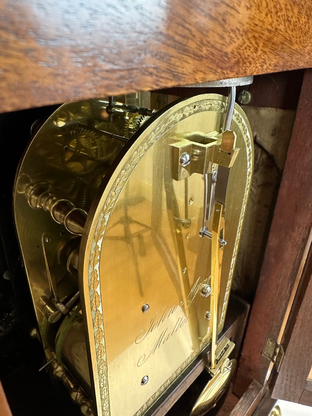 A Georgian mahogany bracket clock featuring a top brass pineapple finial, brass side handles, brass feet, and a arched dial signed John Agar Malton with a strike silent indicator. View XI