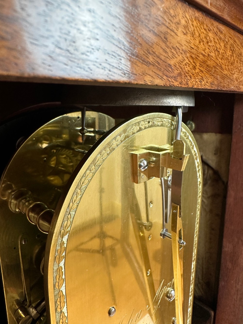 A Georgian mahogany bracket clock featuring a top brass pineapple finial, brass side handles, brass feet, and a arched dial signed John Agar Malton with a strike silent indicator. View XII