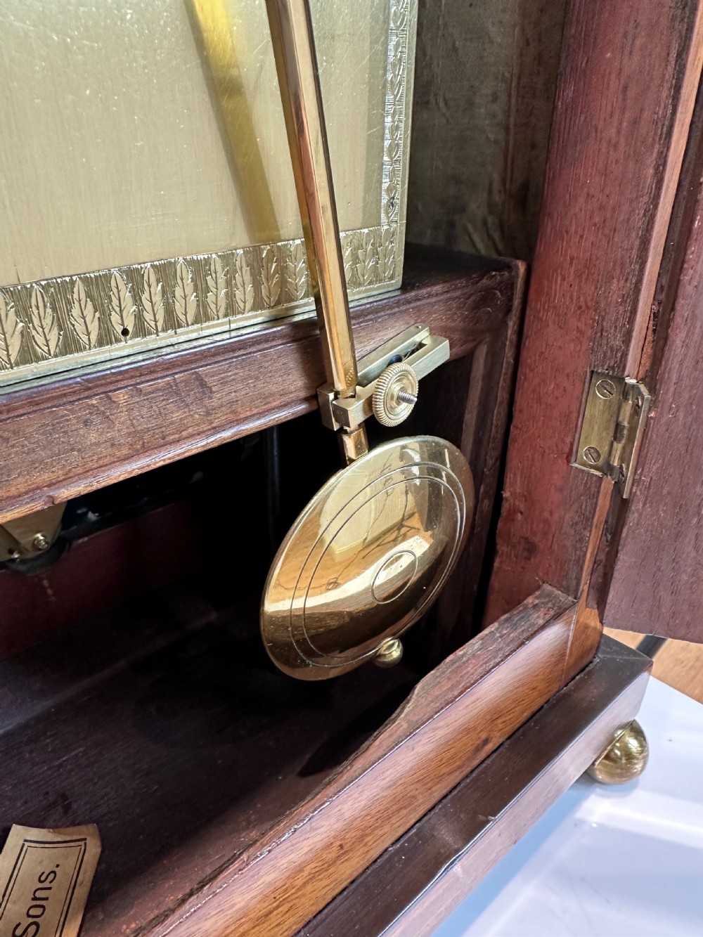 A Georgian mahogany bracket clock featuring a top brass pineapple finial, brass side handles, brass feet, and a arched dial signed John Agar Malton with a strike silent indicator. View XV