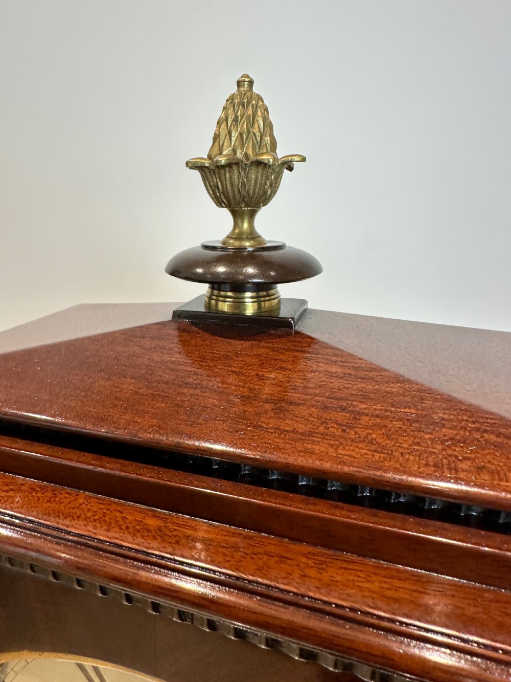 A Georgian mahogany bracket clock featuring a top brass pineapple finial, brass side handles, brass feet, and a arched dial signed John Agar Malton with a strike silent indicator. View XVI