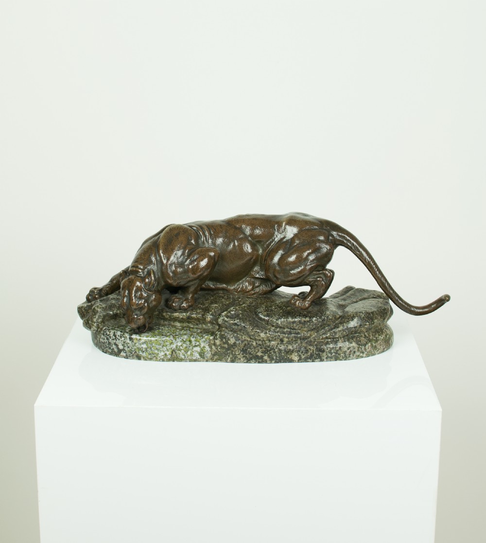 A patinated dark brown bronze sculpture depicting a crouching panther drinking water from a speckled grey stone base. View VII