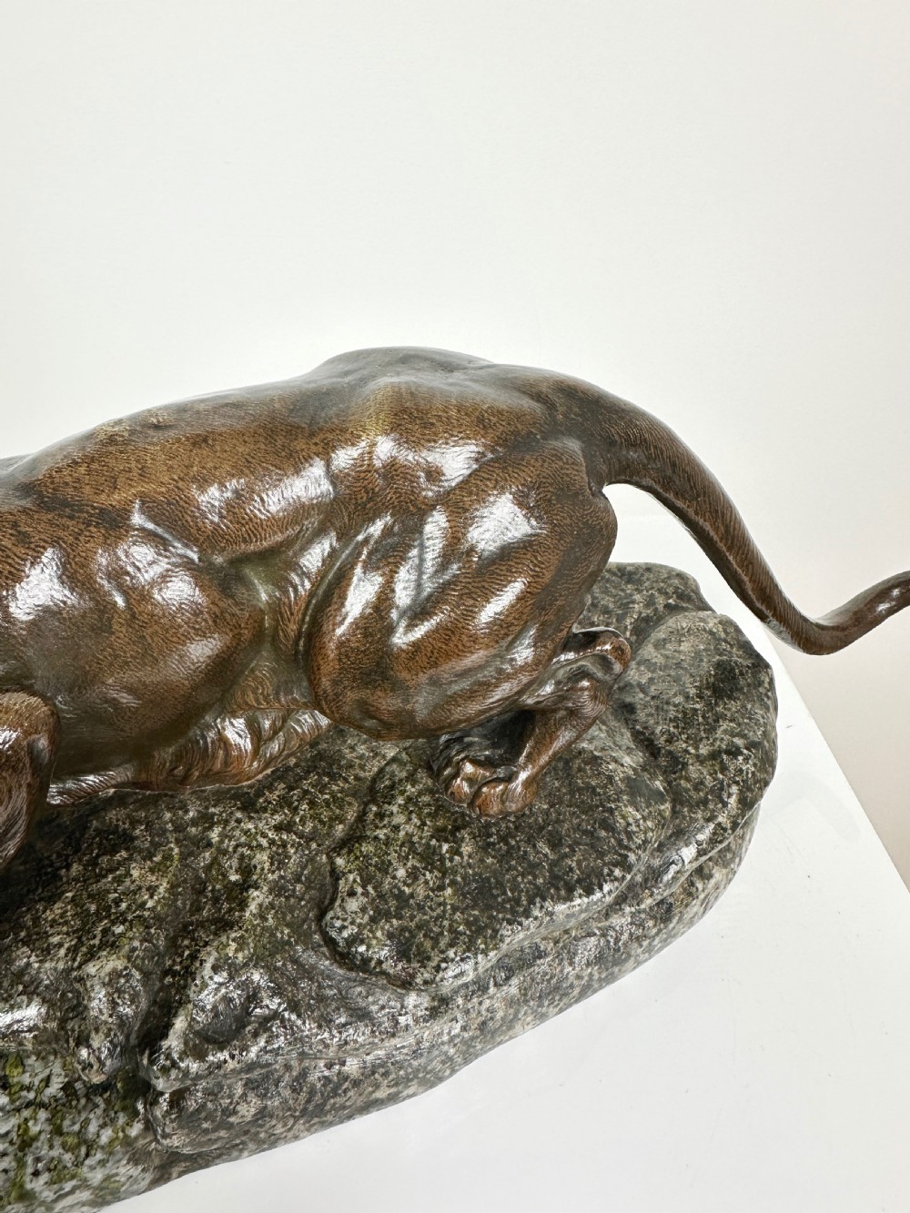 A patinated dark brown bronze sculpture depicting a crouching panther drinking water from a speckled grey stone base. View VIII