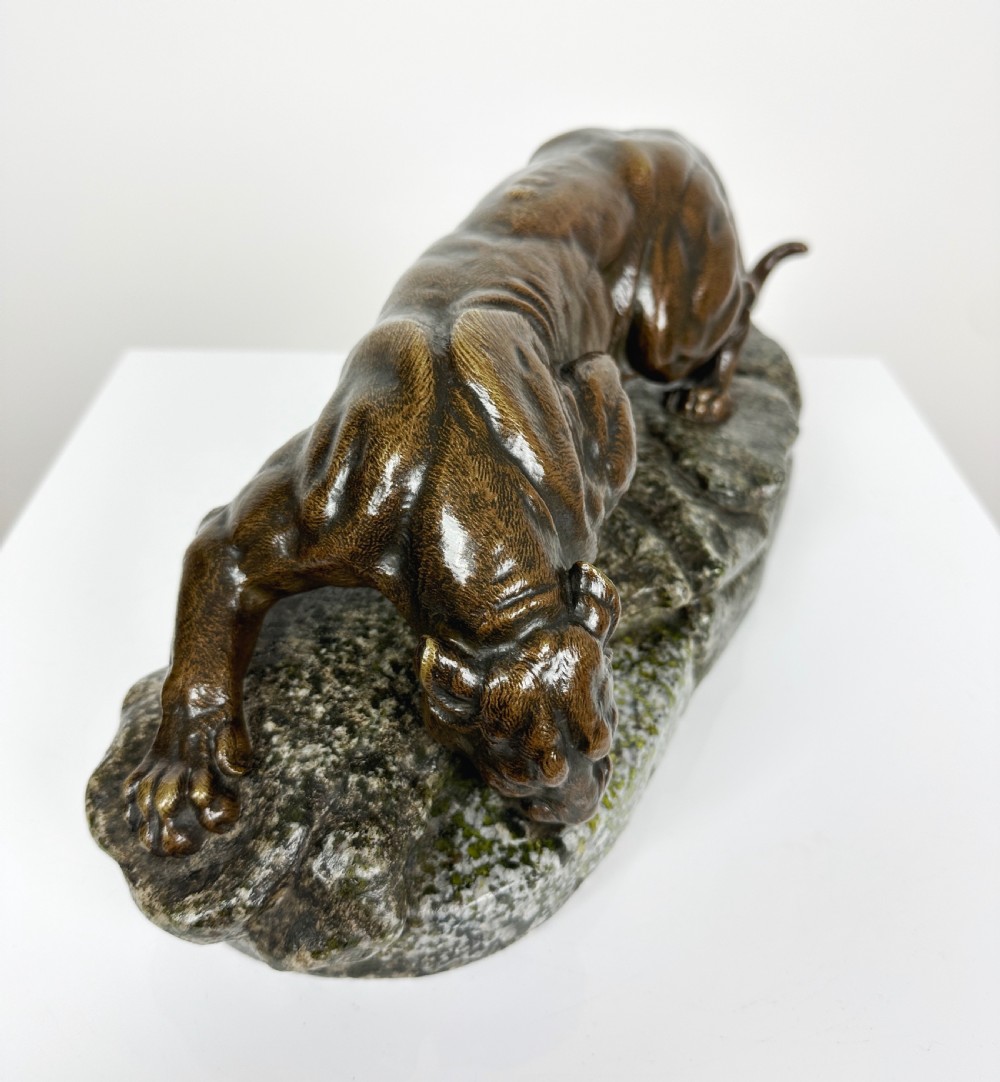 A patinated dark brown bronze sculpture depicting a crouching panther drinking water from a speckled grey stone base. View IX