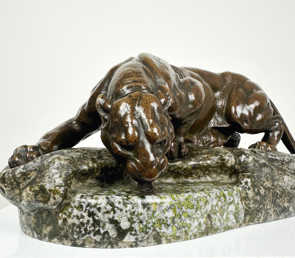 A patinated dark brown bronze sculpture depicting a crouching panther drinking water from a speckled grey stone base. View X