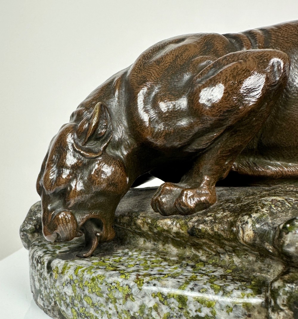 A patinated dark brown bronze sculpture depicting a crouching panther drinking water from a speckled grey stone base. View XIII
