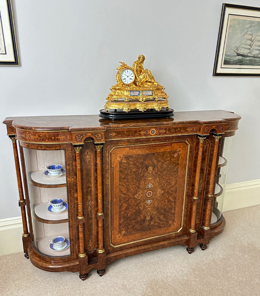 A nineteenth-century French gilt bronze mantel clock featuring a draped classical female figure beside a circular white dial with floral porcelain panels. View IX