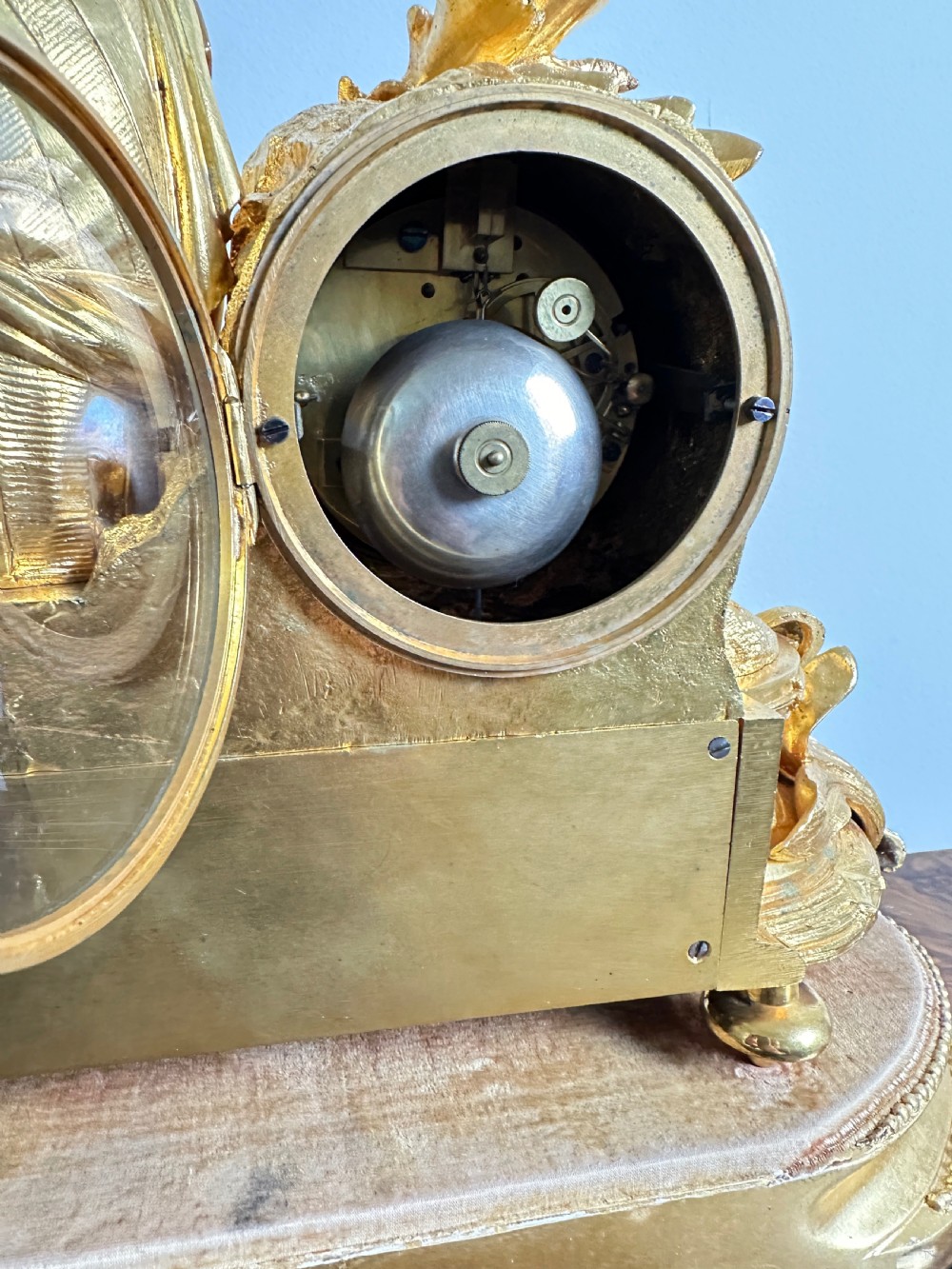 A nineteenth-century French gilt bronze mantel clock featuring a draped classical female figure beside a circular white dial with floral porcelain panels. View XIII