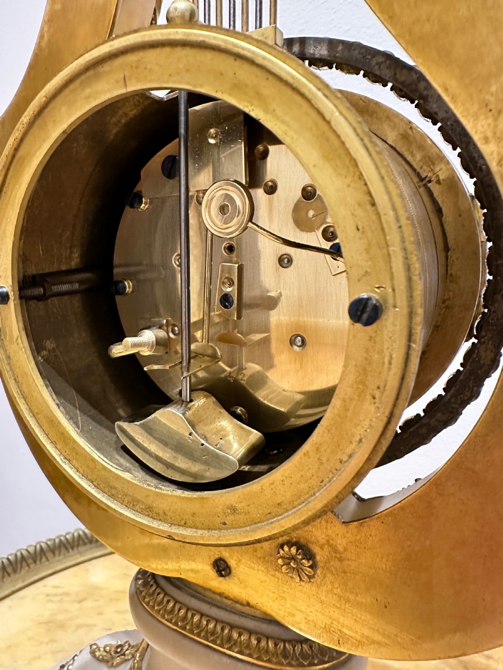 A Louis XVI style white marble and gilt bronze lyre-shaped mantel clock topped with a sunburst Apollo head mask and featuring a crystal-encrusted dial bezel. View VIII