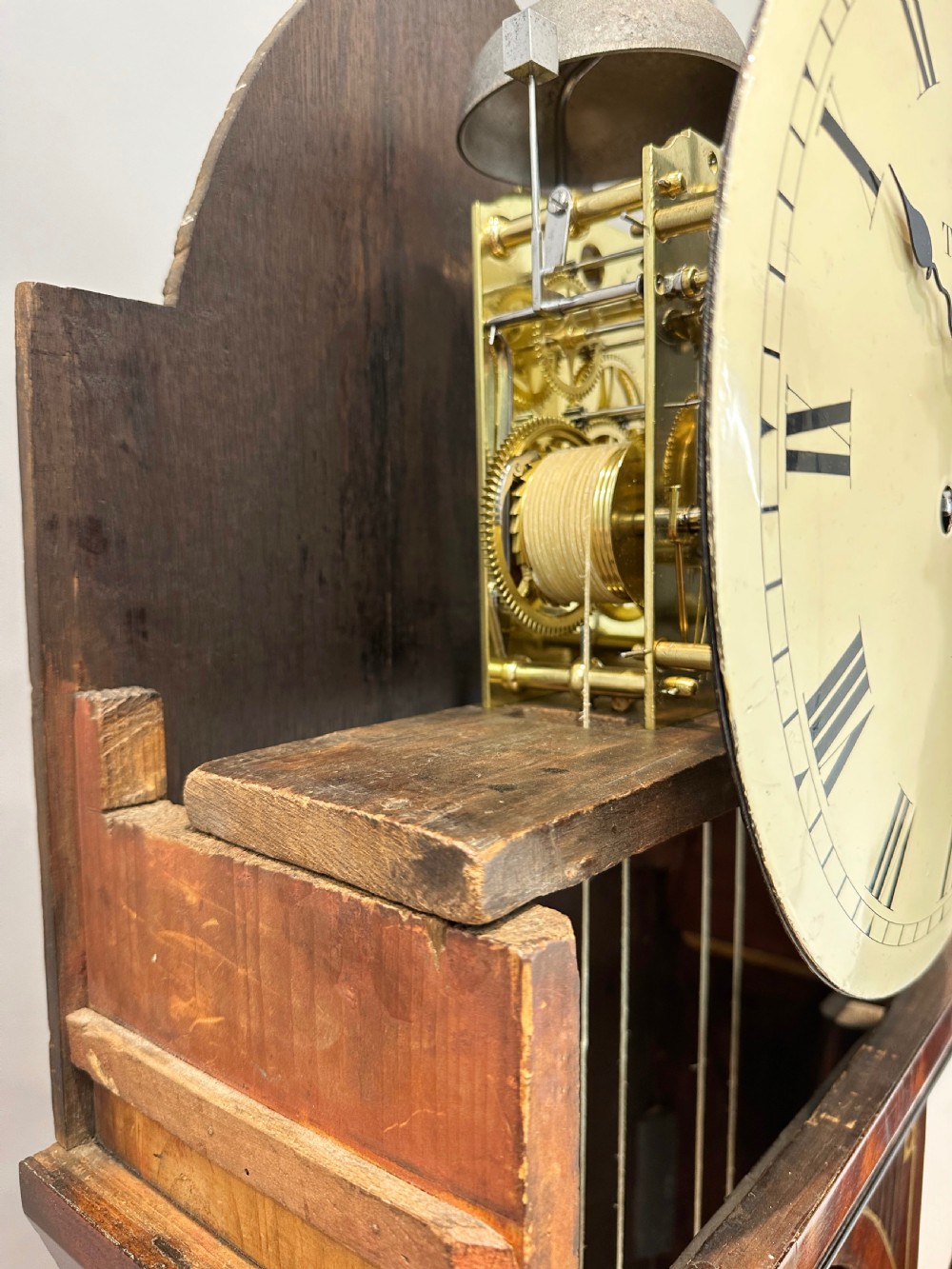 A Regency flame mahogany longcase clock featuring a pointed arch hood, white circular dial signed by Thomas Wightman of London, and brass column details. View IX