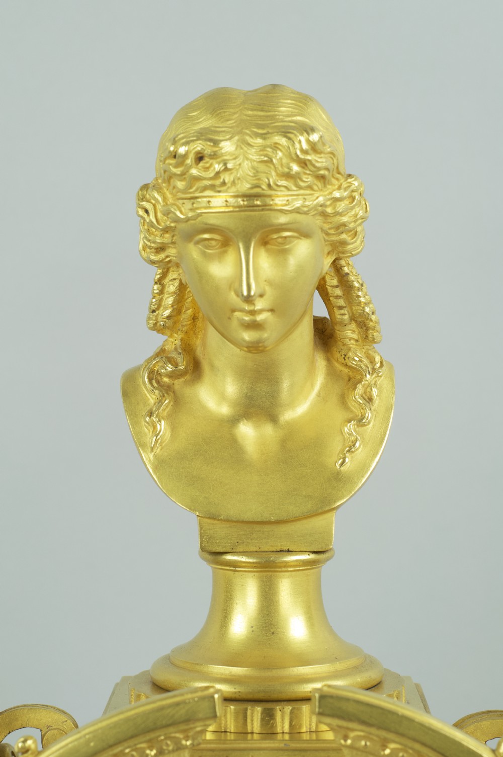 A French ormolu mantel clock featuring a classical female bust finial, blue enamel dial, and flanked by winged griffins on an ornate base. View VII